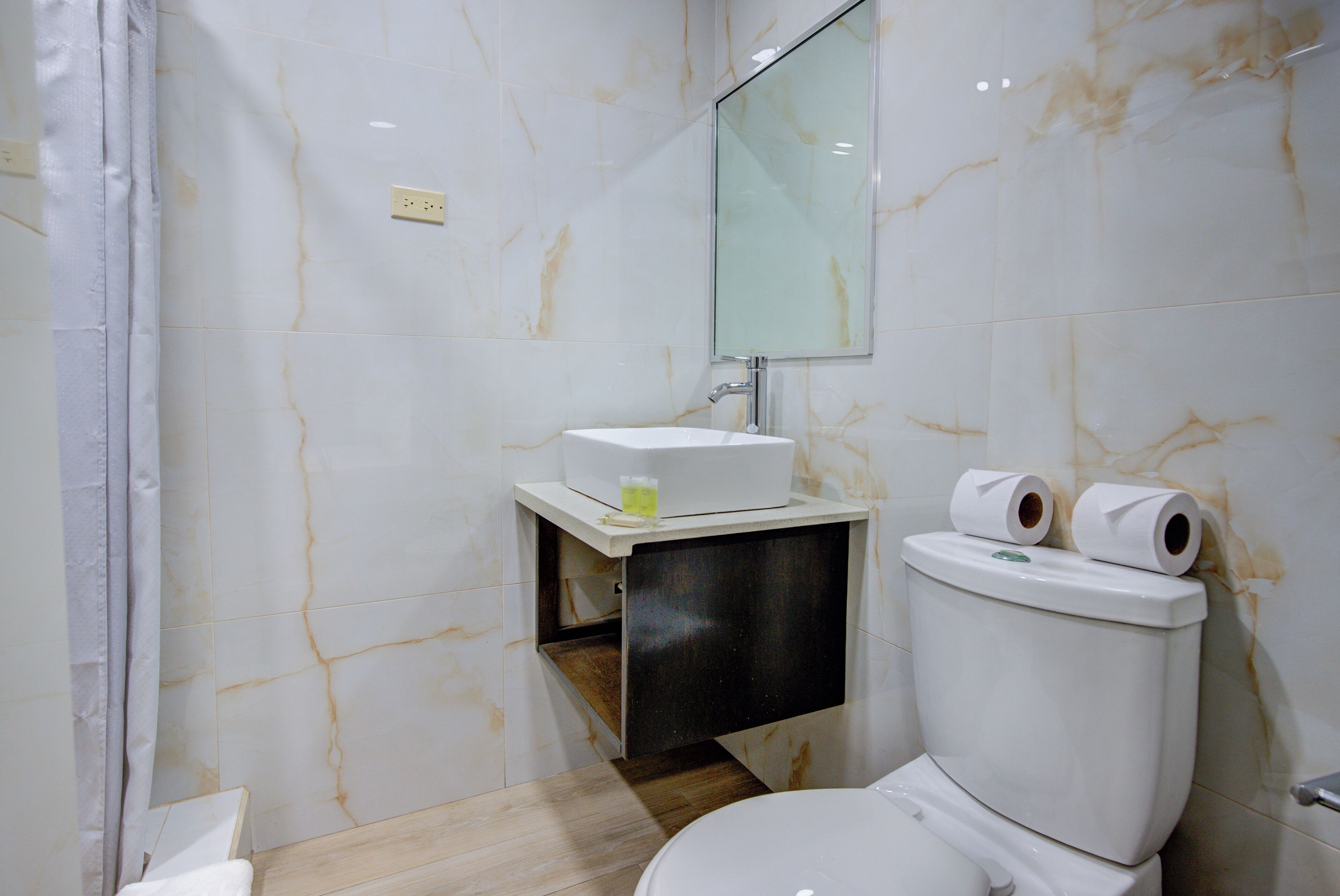 A modern bathroom with a marble floor, a white sink, and a toilet.