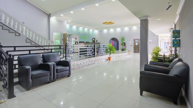 A spacious lobby with a staircase, black leather chairs, and a reception desk.