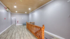 A spacious room with a wooden ceiling, grey walls, and a wooden floor.