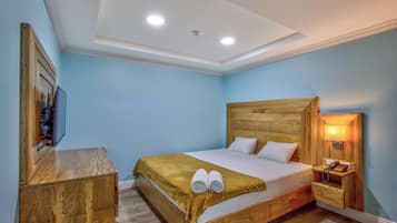 A neatly arranged bedroom with a wooden bed, a bedside table, a nightstand, and a wall-mounted lamp.