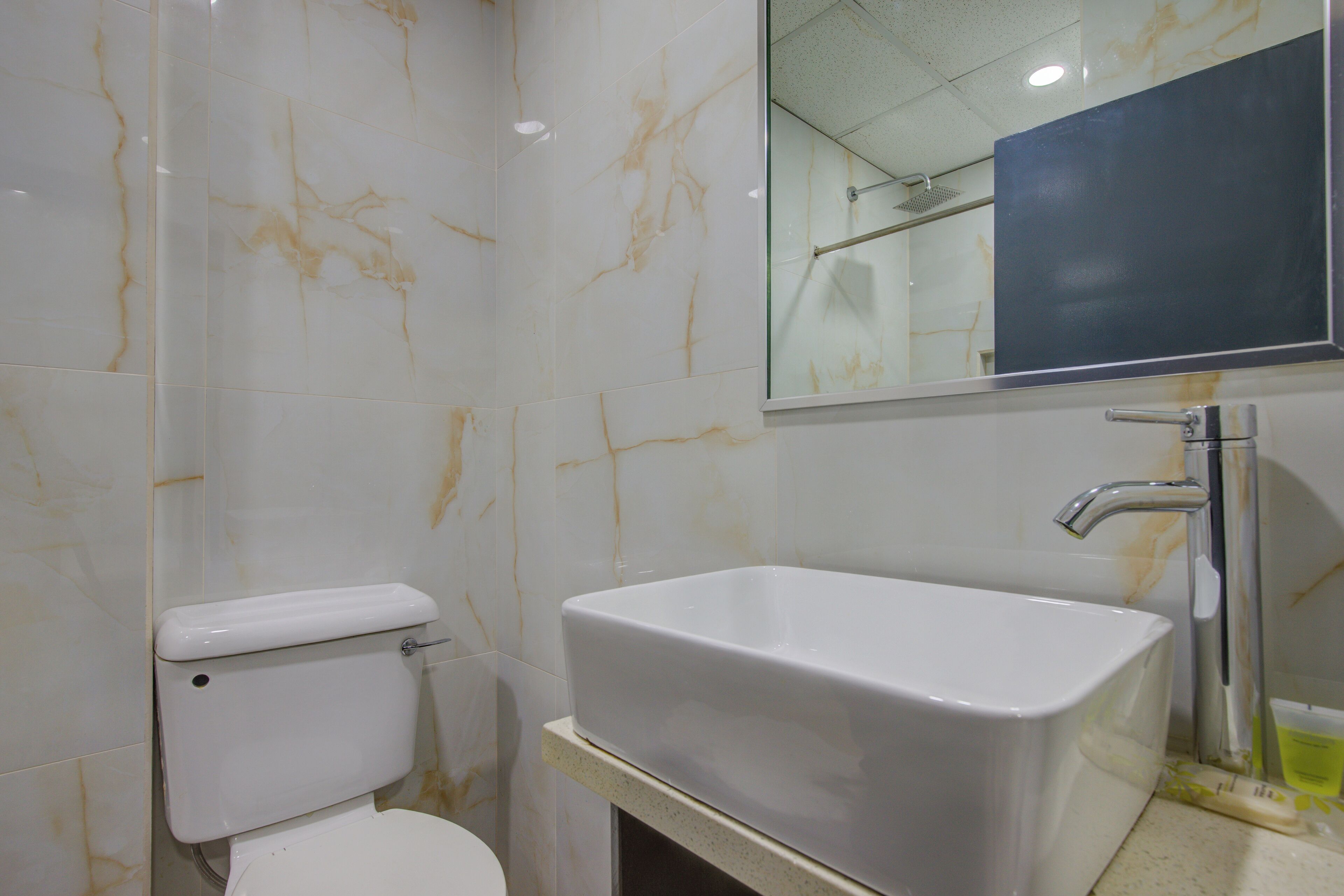 A bathroom with a toilet, a sink, and a mirror.