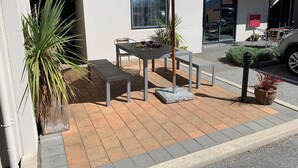 An outdoor patio with a table and chairs, a large umbrella, and potted plants. - Bella Vista Motel Wanaka (Wanaka)