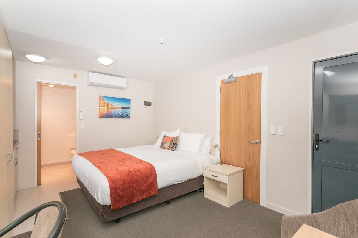 Een hotelkamer met een bed, nachtkastje en een kledingkast.