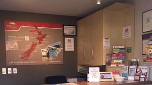 A reception desk with a map of New Zealand, a framed certificate, and travel guides. - Bella Vista Motel Wanaka (Wanaka)