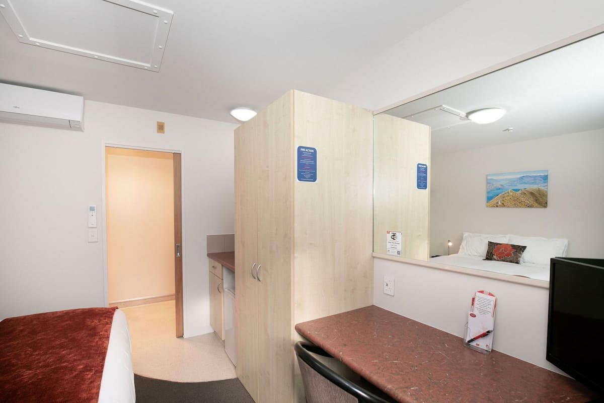 Een hotelkamer met een bed, een bureau, een spiegel en een televisie.