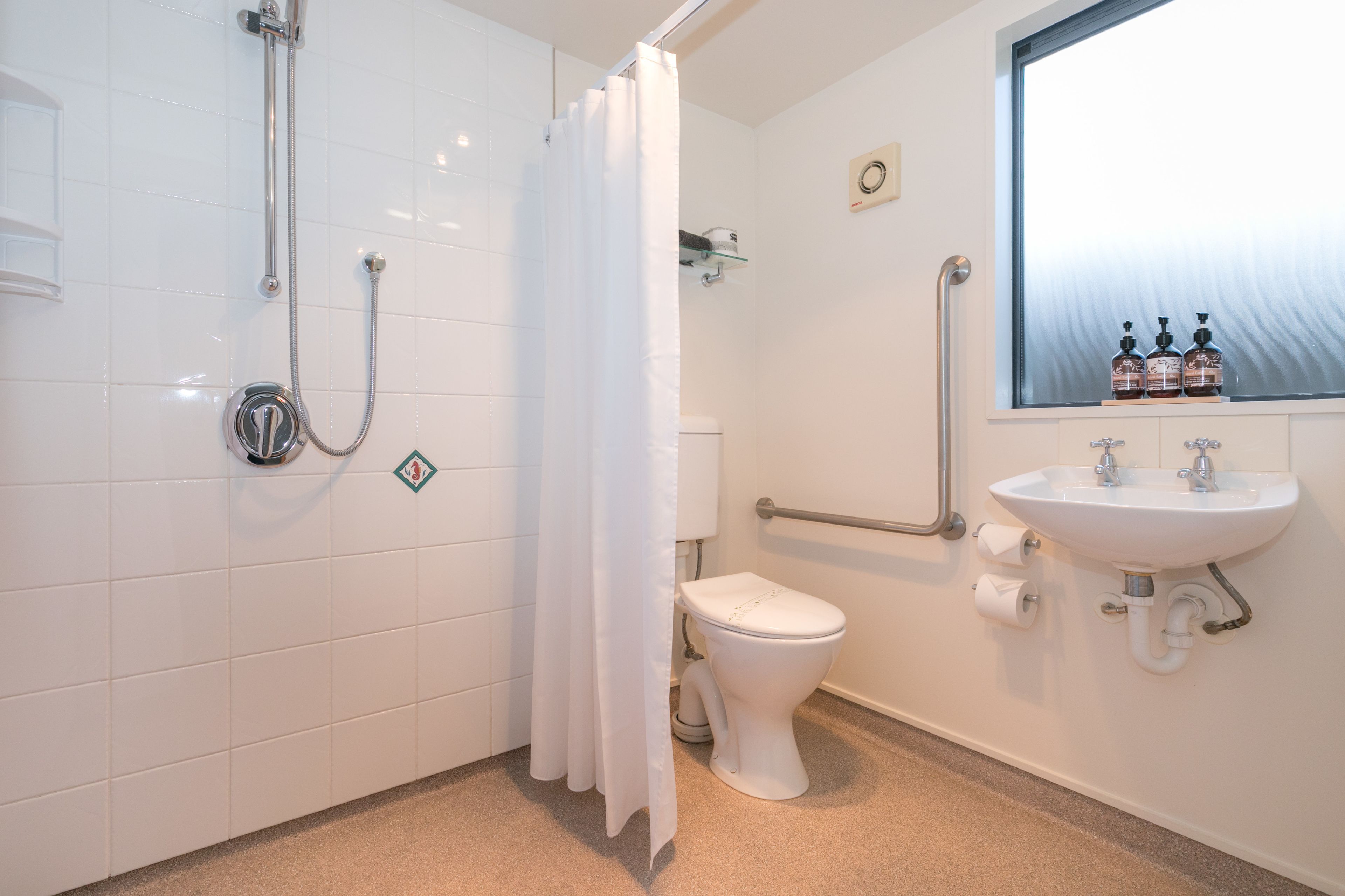 A bathroom with a shower, toilet, and sink.