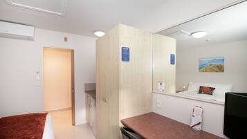 A hotel room with a bed, a desk, a TV, and a wardrobe.