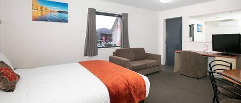 A hotel room with a bed, a desk, a chair, and a television.