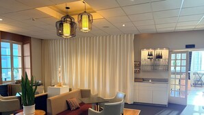 A modern hotel lobby with a seating area, a bar, and a view of the outdoors. - Grand Hotel (Mayenne)