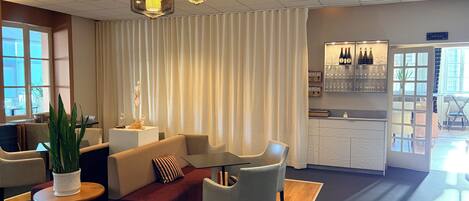 A modern hotel lobby with a seating area, a bar, and a view of the outdoors.