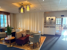 A modern hotel lobby with a seating area, a bar, and a view of the outdoors.