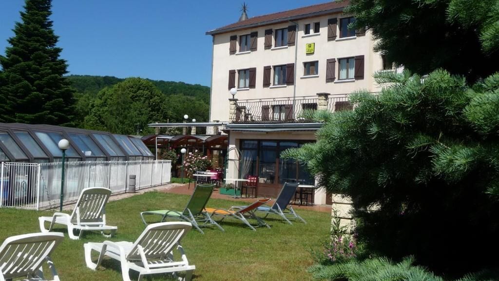 Un hôtel doté d’un espace extérieur abrité, de chaises longues et d’un bâtiment comportant de nombreuses fenêtres et balcons.
