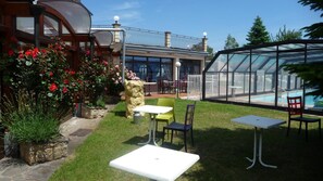 Un patio con mobiliario exterior, piscina y un invernadero.