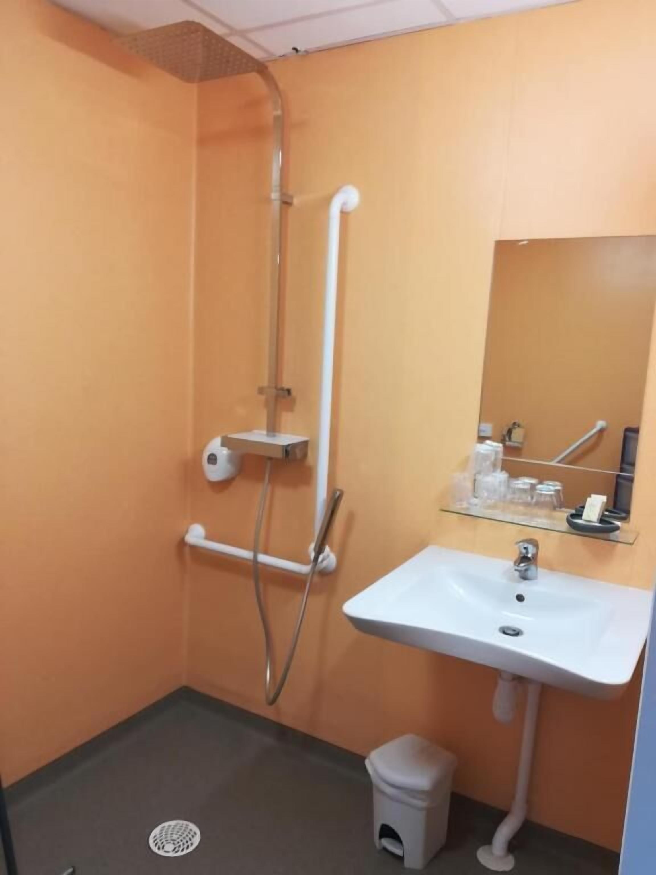 Une petite salle de bain avec une douche, un lavabo et un miroir.