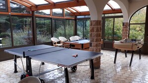 A sunlit indoor space with a ping pong table, a foosball table, and a pool table. - Logis La Rose des Vents (Volvic)