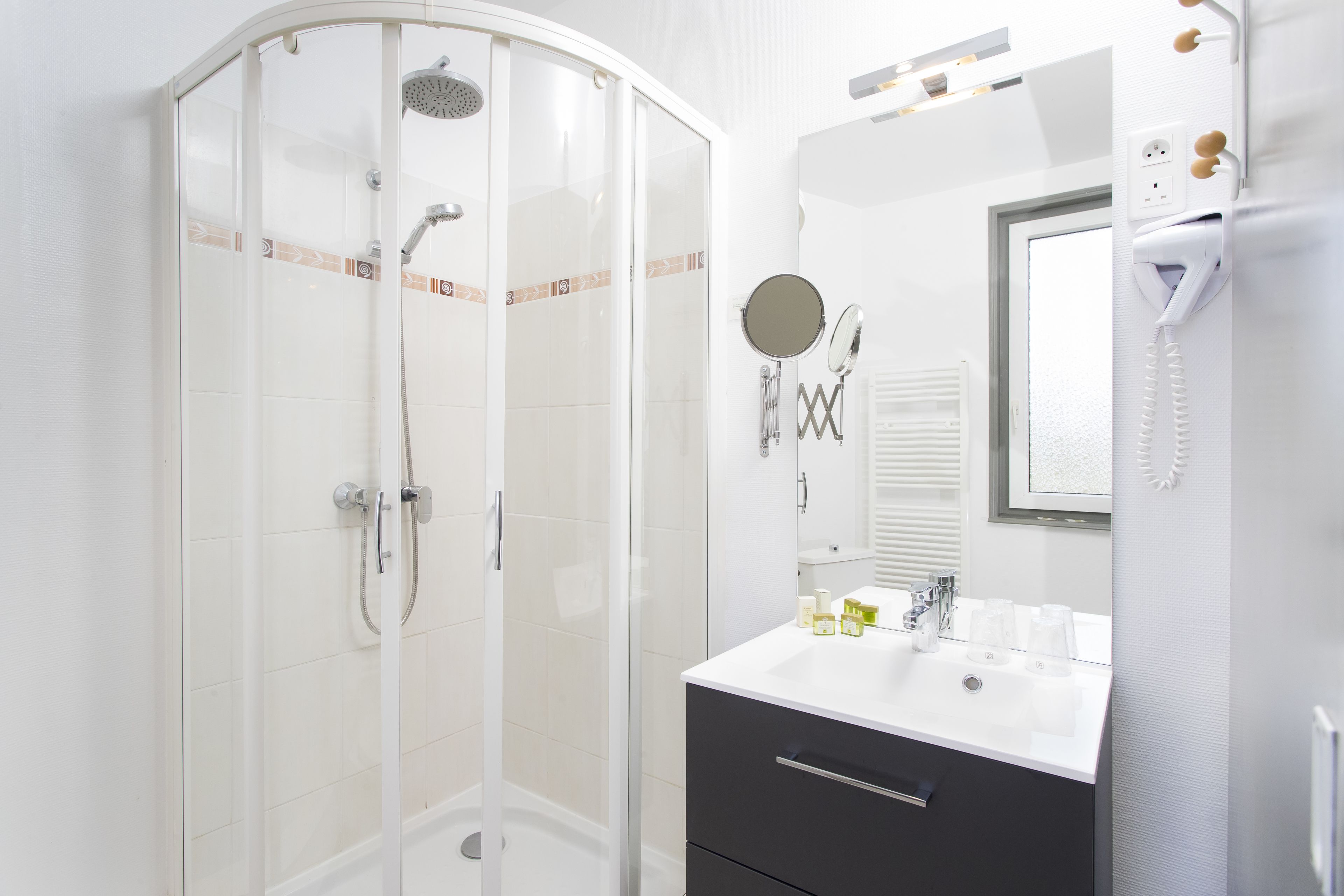 Une salle de bain moderne avec une douche à parois de verre, un lavabo blanc avec un miroir et un porte-serviettes.