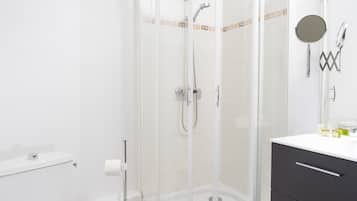 A modern bathroom with a glass-enclosed shower, a white toilet, and a black vanity with a mirror.