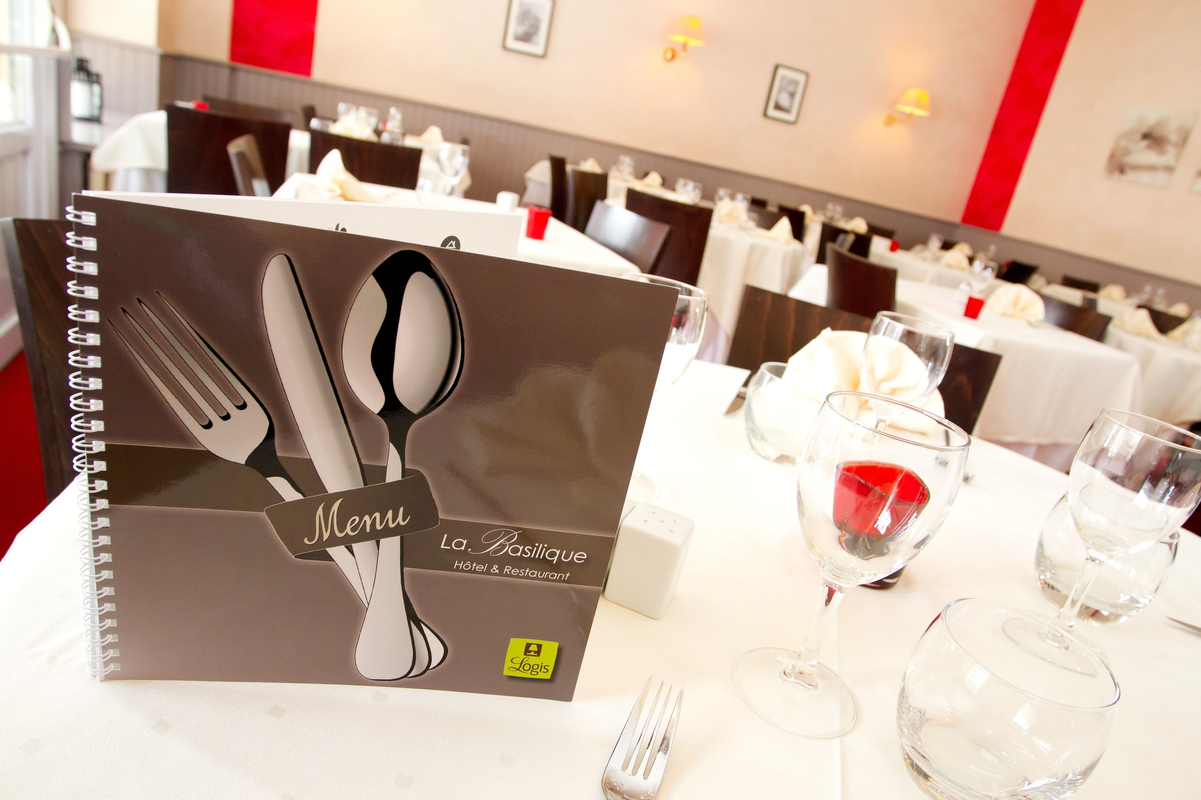 A restaurant setting with a menu book and tableware.