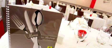 A restaurant setting with a menu book and tableware.