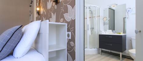 Un dormitorio con cama, mesita de noche y baño privado con ducha, inodoro y tocador.