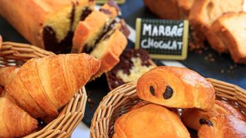 Diversitat de pastissos, incloent croissants i pa de xocolata, exposats en cistos de vimet.