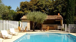 A swimming pool with lounge chairs and a small building in the background.