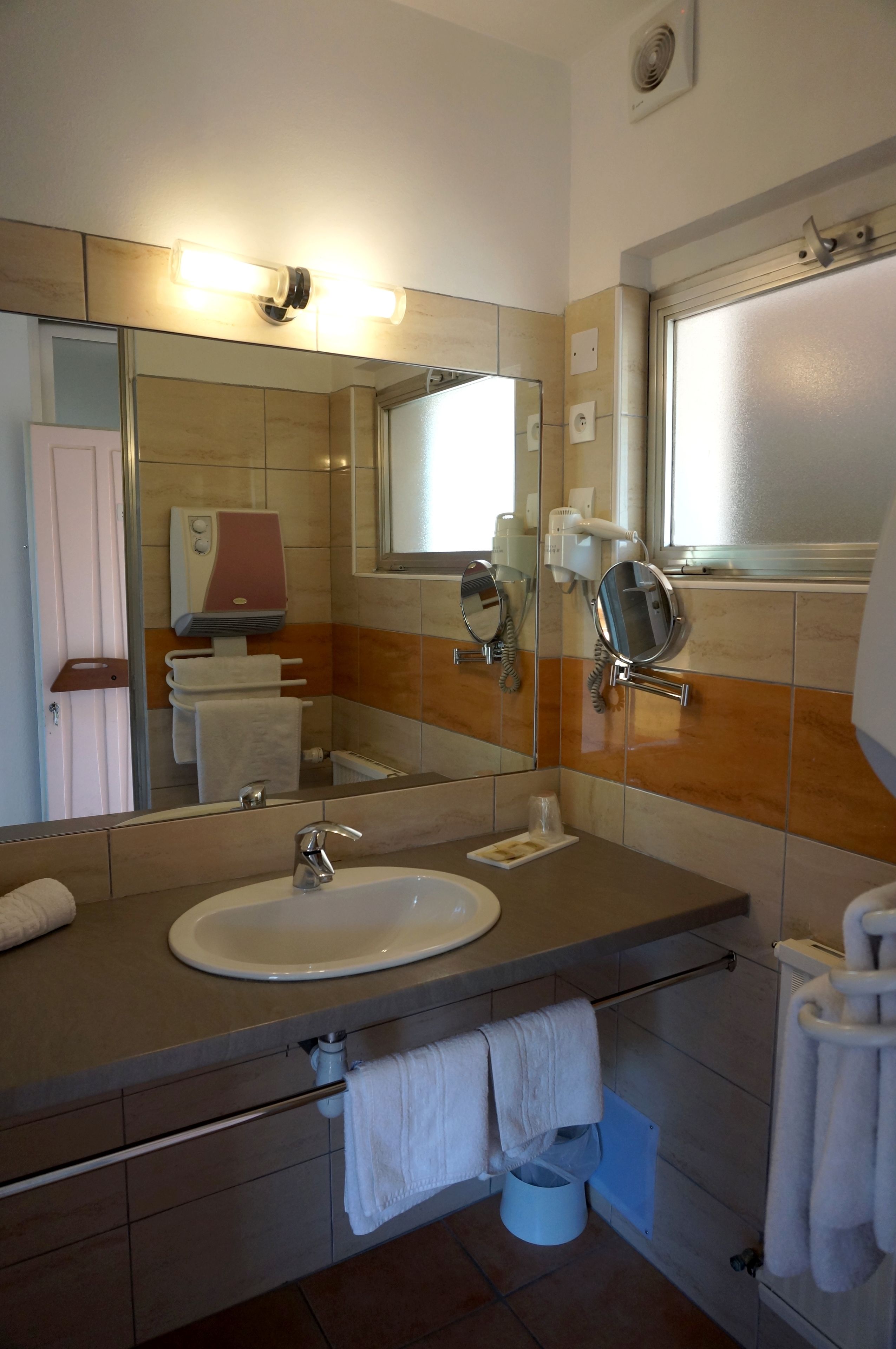 A bathroom with a sink, mirror, towel rack, and a hand dryer.