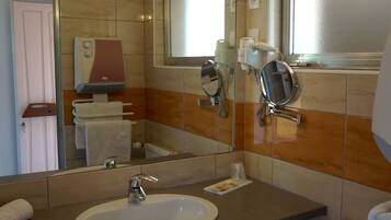 Une salle de bain équipée d’un lavabo, d’un miroir, d’un porte-serviettes et d’un sèche-mains.