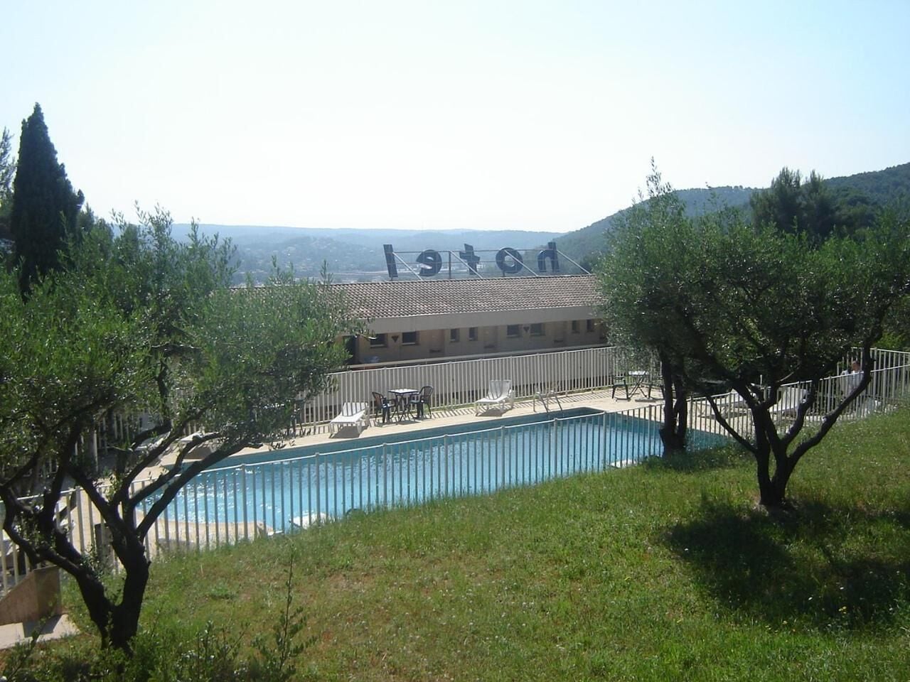A hotel with a swimming pool, outdoor seating, and a view of the surrounding landscape.