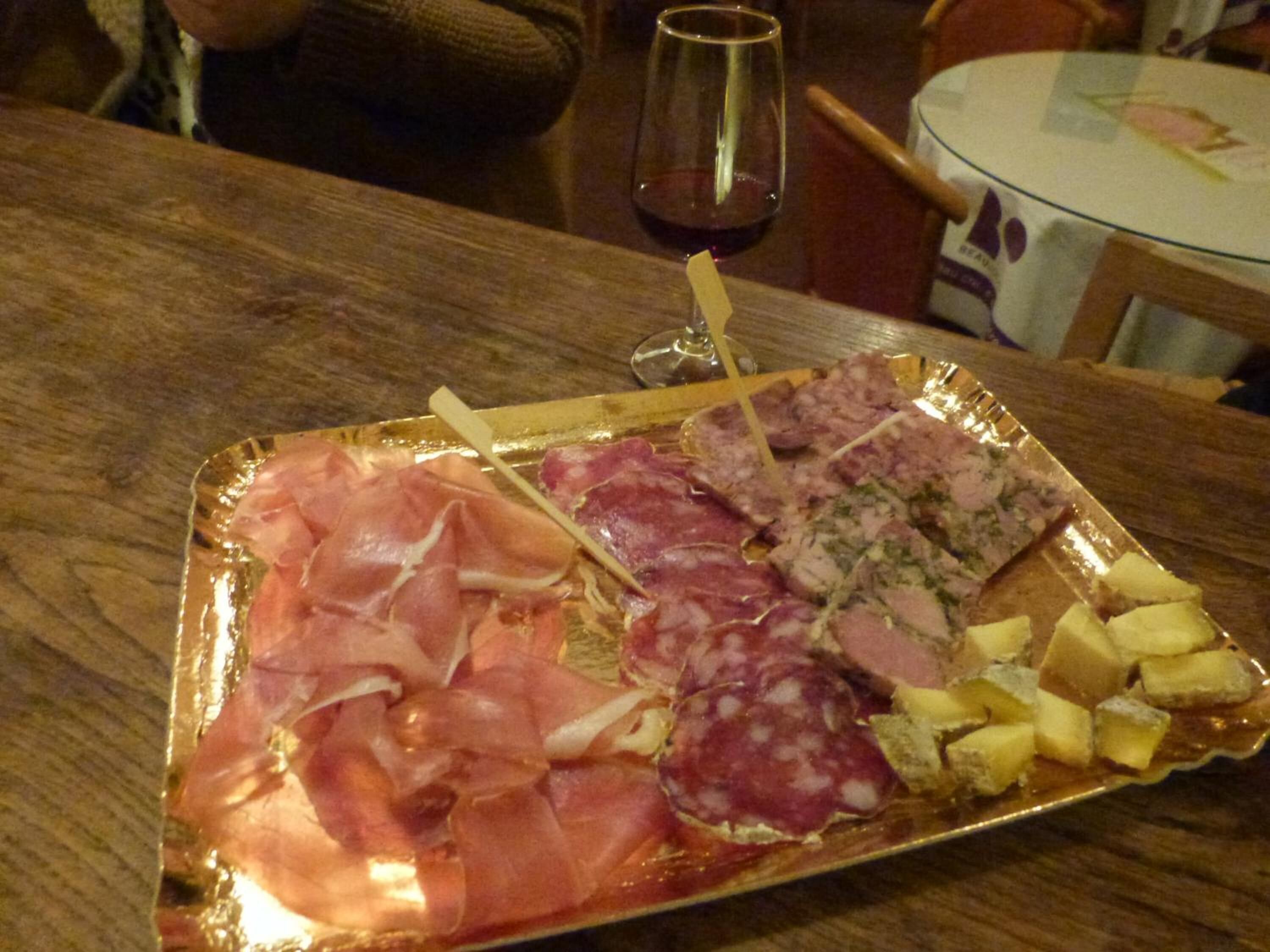 Una bandeja con variedad de embutidos y quesos sobre una mesa de madera.