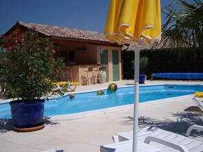 Una piscina al aire libre, sombrillas, sillones reclinables de piscina