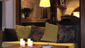 A cozy seating area with a sofa, cushions, a table, and candles.