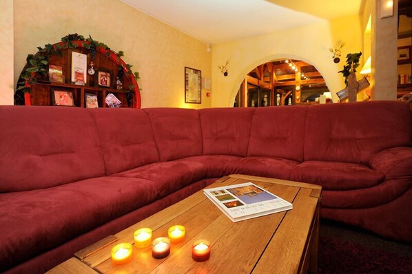A red sofa in a warmly lit room with a wooden coffee table and lit candles.