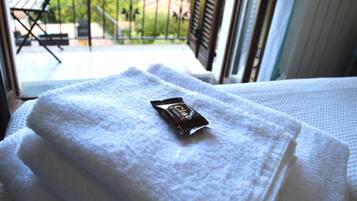 A neatly folded white towel with a chocolate bar on a bed.