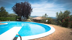 A swimming pool with a white deck, surrounded by a brick patio, a metal fence, and a tree. - Antiche Terre Hotel & Relax (Pignone)