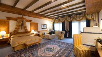 A traditional room with a large bed, a wooden ceiling, a patterned rug, and a small table with a vase of flowers.