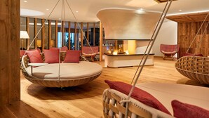 A cozy room with a hanging chair, a round seating area, and a fireplace. - Hotel Sassongher – Preferred Hotels & Resorts (Corvara in Badia)