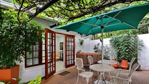A patio with a table and chairs, a green umbrella, and potted plants. - Rivonia Premier Lodge (Johannesburg)