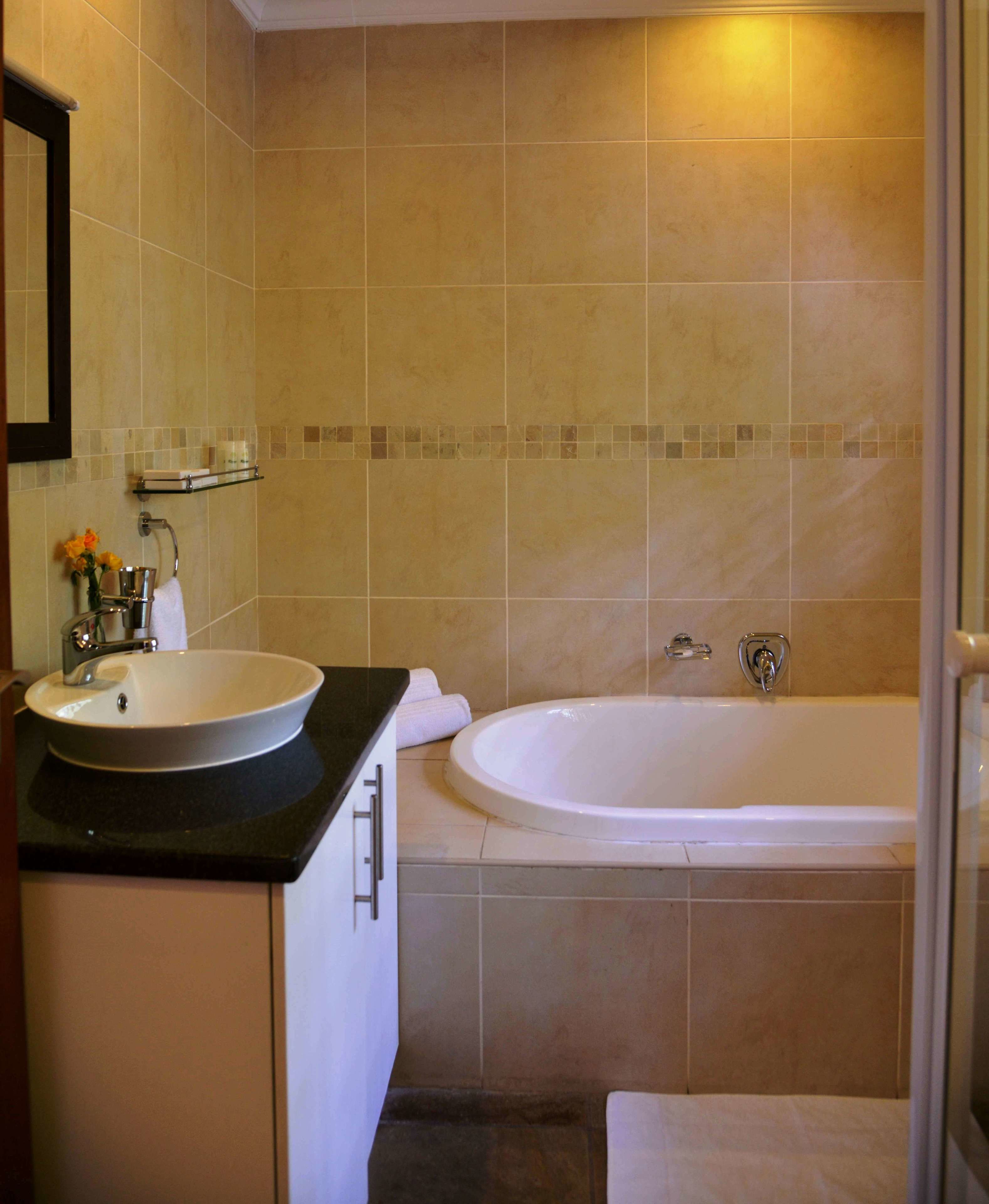 A bathroom with a sink, mirror, and bathtub.