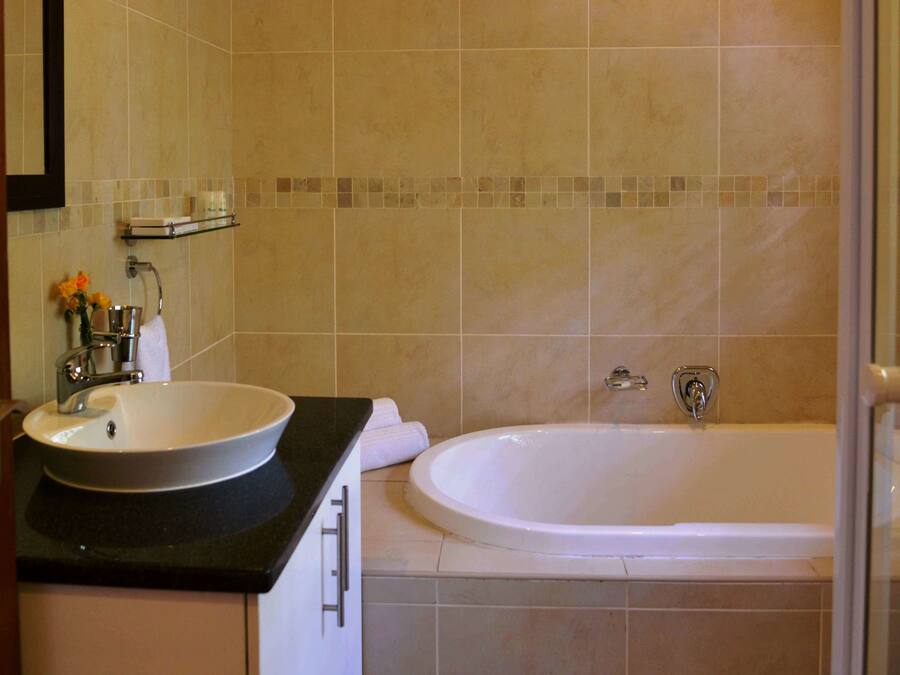 A bathroom with a sink, mirror, and bathtub.