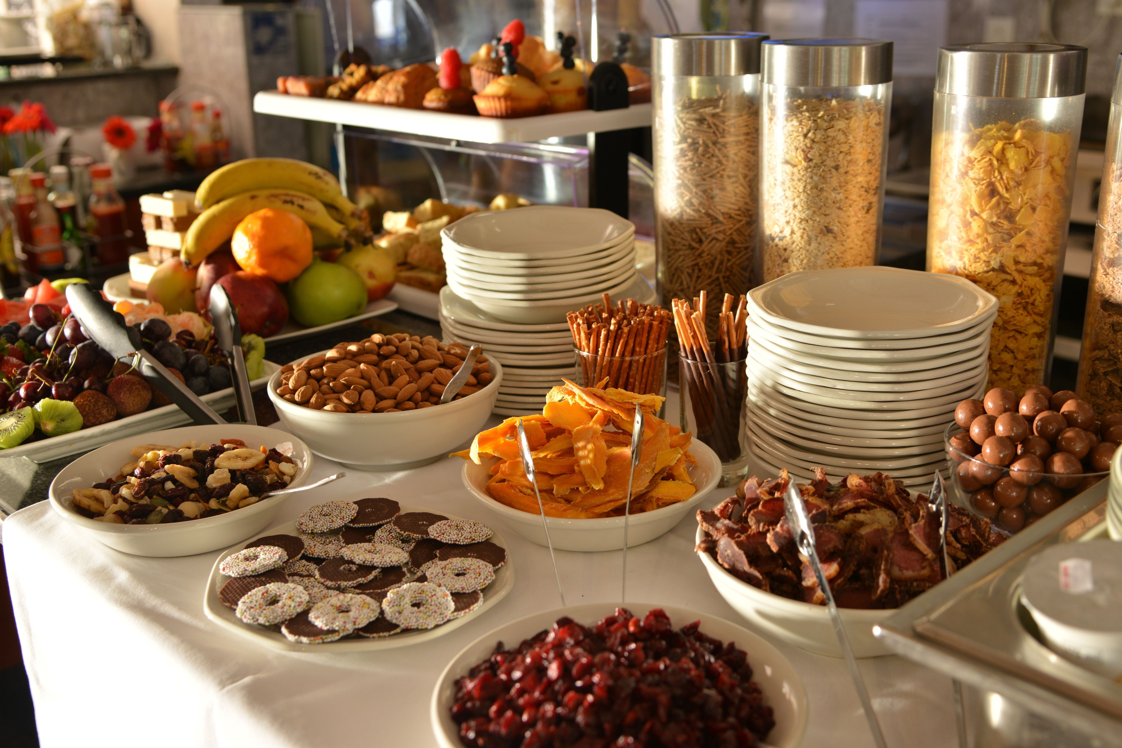 A buffet with various food items including fruits, nuts, pastries, and cereals.