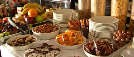A buffet with various food items including fruits, nuts, pastries, and cereals.