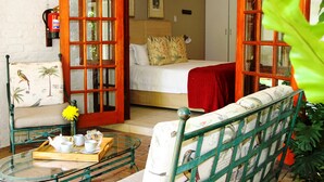 A room with a bed, a chair, a table with a tray, and a door leading to another room. - Rivonia Premier Lodge (Johannesburg)