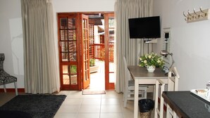 A room with a bed, a desk with a computer, a TV, and a window with curtains. - Rivonia Premier Lodge (Johannesburg)