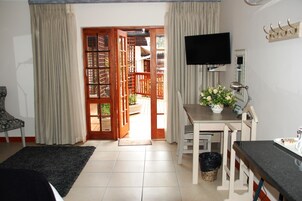 A room with a bed, a desk with a computer, a TV, and a window with curtains.