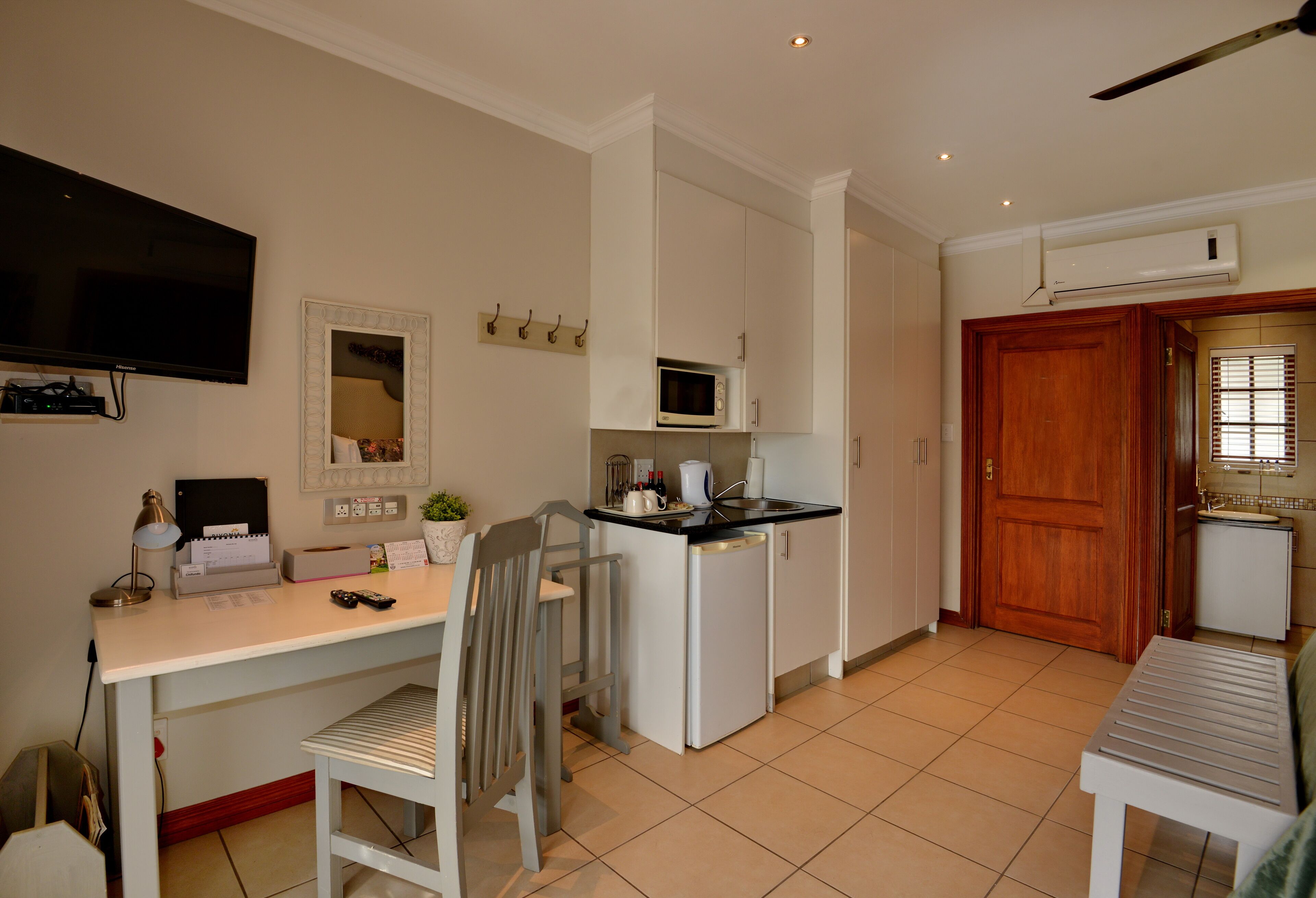 A compact kitchen with a microwave, sink, and a small refrigerator. There is a dining area with a table and chairs.