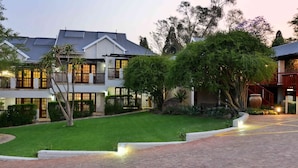 A two-story building with a well-maintained lawn and a brick pathway leading to the entrance. - Rivonia Premier Lodge (Johannesburg)