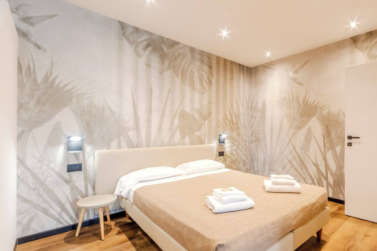 A modern bedroom with a bed, bedside tables, and a wardrobe.