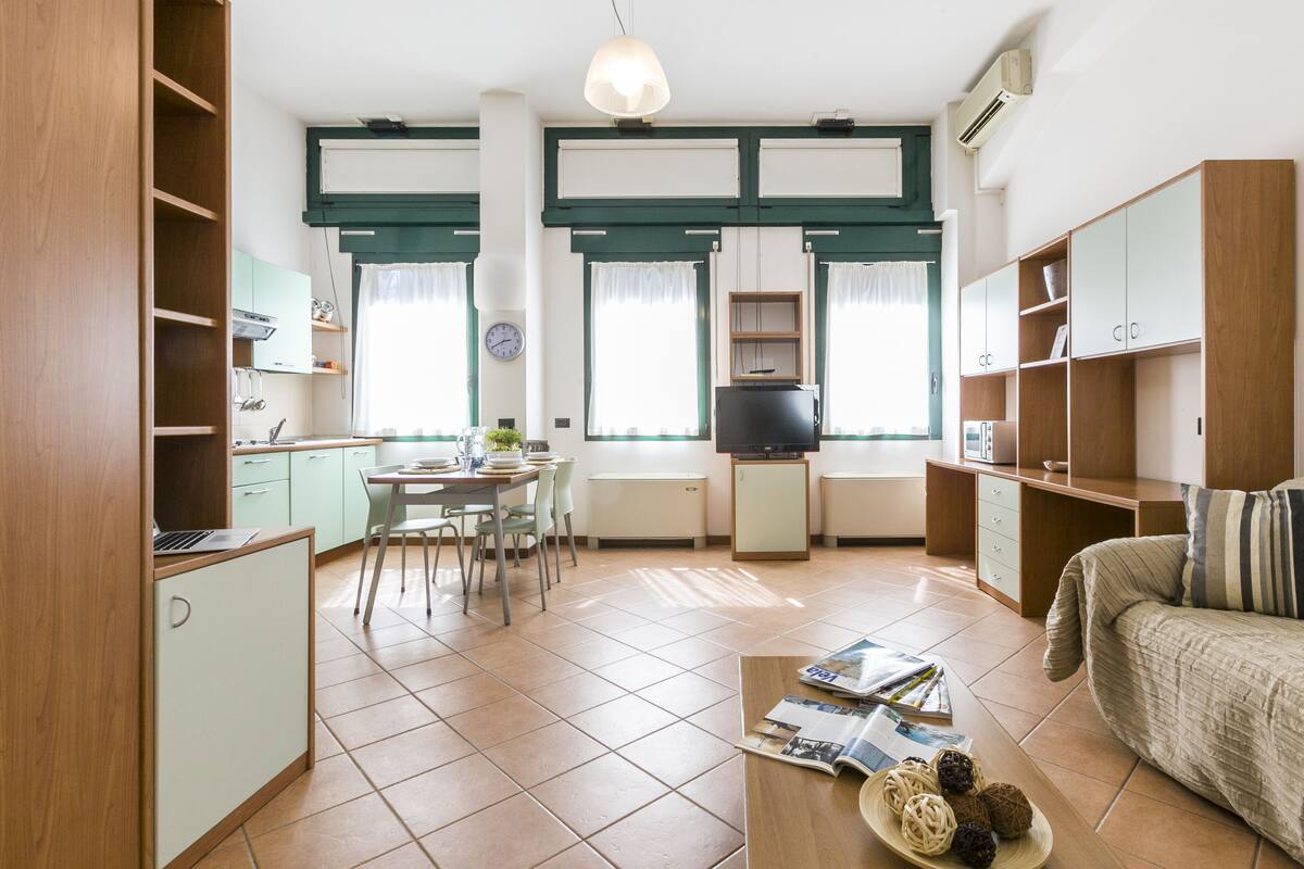 A compact living space with a kitchenette, dining area, and a sofa.