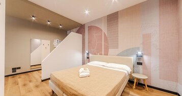Un dormitorio moderno con una cama, una mesita de noche, un espejo y una escalera.